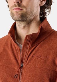 Giacca in fleece con zip di colore arancione bruciato, con colletto alto, tessuto strutturato e logo ricamato. Presenta una zip frontale e un cordino.