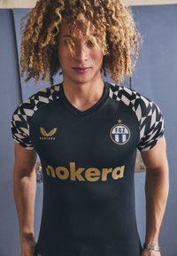 Schwarzes Sporttrikot mit kurzen gemusterten Ärmeln. Mit goldenen Buchstaben und einem Logo auf der Brust, hergestellt aus leichtem, flexiblem Material.