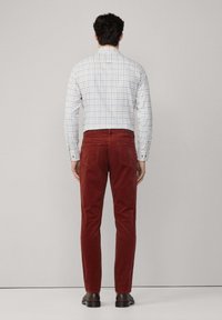 Rote Cordhosen mit schlanker Passform, kombiniert mit einem karierten Button-Down-Hemd. Verfügt über einen standardmäßigen Bund und Gesäßtaschen.