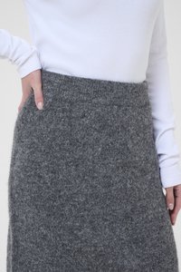 Grey felt skirt with a high, elastic waistband. Soft texture, no visible patterns, and a straight design. Hand resting on the waistband.