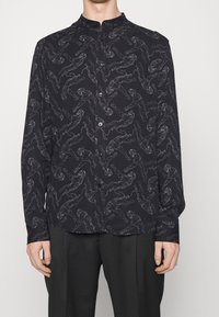 Zwart shirt met lange mouwen met een wit tijgerpatroon, ronde hals, knoopsluiting aan de voorkant en een gladde stoffen textuur.