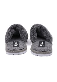 Chaussons en tissu gris avec une tige texturée et duveteuse, dos ouvert, et semelle en caoutchouc blanc ornée d'un logo sur un patch noir.