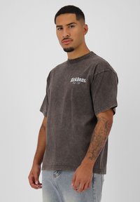 Grijze oversized t-shirt met een licht vervaagde textuur, voorzien van een logo op de borst, korte mouwen en een ronde hals.