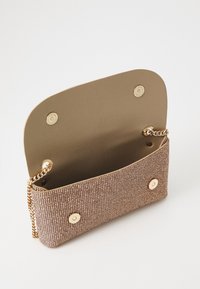 Kopertówka z beżowej tkaniny o fakturze, z złotymi akcentami. Otwiera się szeroko za pomocą metalowych zatrzasków i ma łańcuszkowy pasek. Gładka podszewka wewnętrzna.