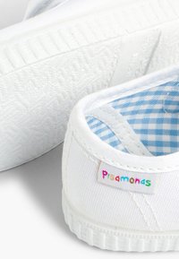 Scarpe da tela bianche con fodera a quadri blu e suola in gomma testurizzata. Presenta un colorato etichetta "Pisamonas" sul lato.