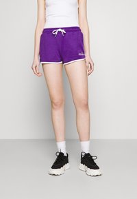 Shorts en coton violets avec des bordures blanches, dotés d'une taille ajustable avec cordon de serrage et d'un logo brodé sur le côté gauche.