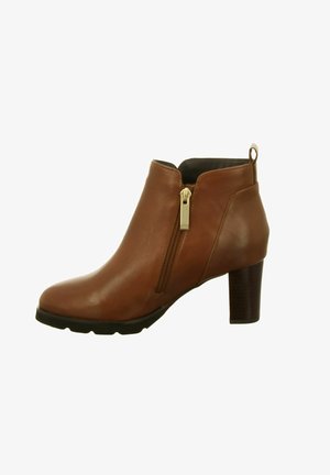 Botte cheville en cuir marron avec fermeture éclair latérale, languette de traction, bout arrondi et talon bloc empilé sur fond blanc.