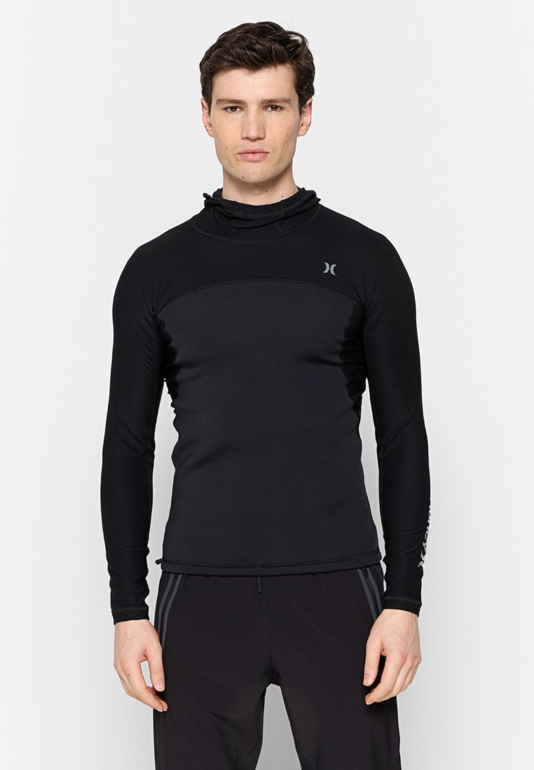 Czarna, długorękawowa koszulka sportowa z wysokim kołnierzem i dopasowanym krojem. Posiada teksturowane wstawki oraz akcenty marki w kontrastowym kolorze.