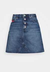 Jeanskjol i mörkblått med åtsittande midja, knappstängning och diagonala sömdetaljer. Har en liten ficka med randigt mönster.