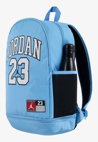 Lys blå ryggsekk har en polstret design, fremtredende "JORDAN" bokstaver, en sidemen pocket for en flaske, og en svart panelaccent.