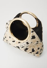 Tan and black patterned handbag with gold circular handles and a black interior. Features a soft texture and structured shape.