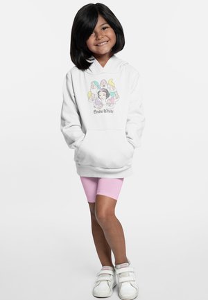 Vitt hoodie med en färgglad grafik av Snövit och dvärgar på framsidan, kombinerat med rosa cykelshorts och vita sneakers.