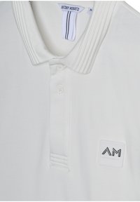 Polo shirt bianco con colletto a costine, tre bottoni e un'etichetta testurizzata con il logo "ANTONY MORATO" in nero. Tessuto morbido.