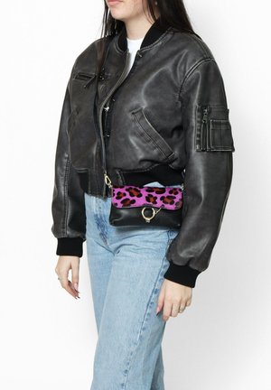 Giubbotto bomber in pelle nera con un design corto, polsini a costine, abbinato a una borsa a tracolla con stampa leopardata nera e rosa.