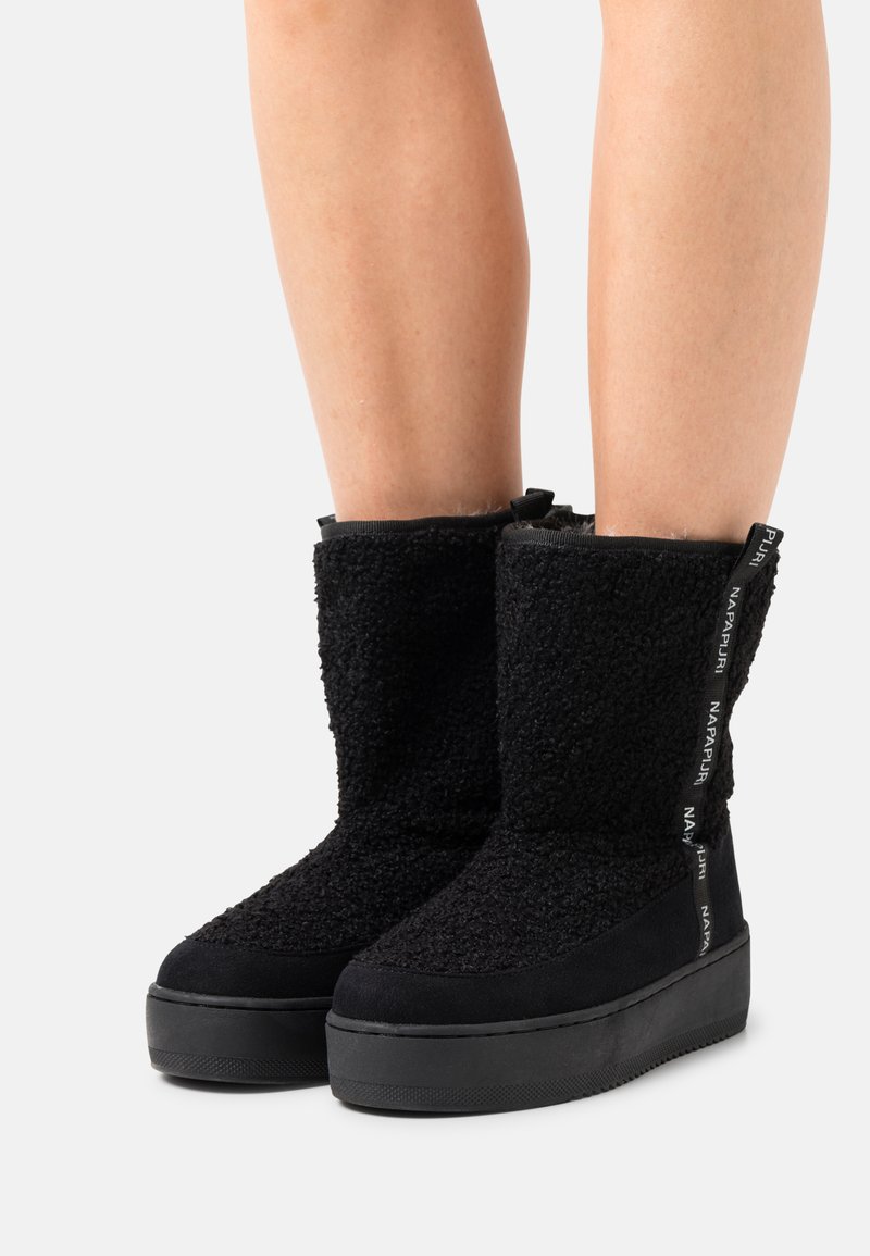 Stivali neri fino al polpaccio realizzati in un materiale texturizzato e morbido, con una suola resistente, accentuati da un'etichetta in tessuto con logo sul retro.