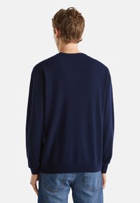 Dunkelblauer gestrickter Pullover mit Rundhalsausschnitt, gerippten Bündchen und Saum. Die Rückseite zeigt eine glatte Textur und eine lockere Passform. Kombiniert mit Jeans.