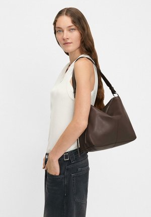 Ciemnobrązowa skórzana torebka o miękkim, luźnym kształcie. Posiada regulowany pasek oraz delikatne detale w szyciu. Nosi się na jednym ramieniu.