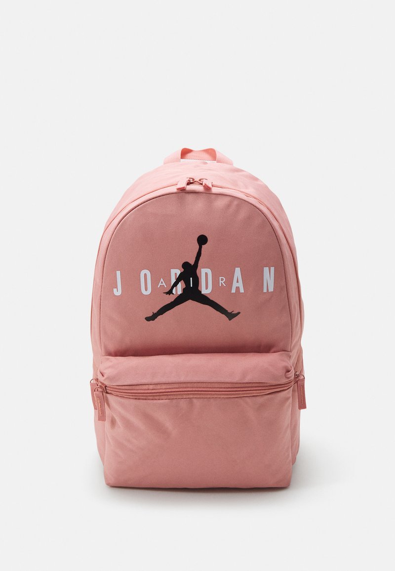 Zaino in tela rosa con logo Jordan nero, tasca frontale con zip e spallacci regolabili. Presenta cuciture a punto e una parte superiore arrotondata.