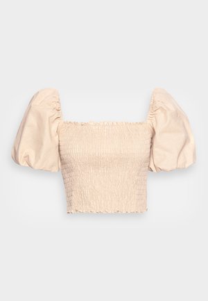 Top corto a maniche corte color beige con texture smock, caratterizzato da maniche a sbuffo e un collo ondulato. Realizzato in tessuto leggero.