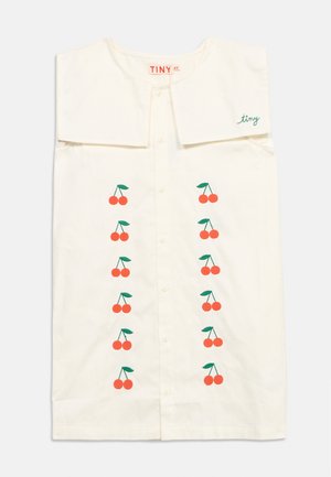 Chemise couleur crème avec un col large, une fermeture à boutons sur le devant, et deux rangées verticales d'illustrations de cerises rouges avec des tiges et feuilles vertes.