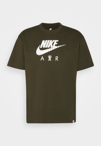 Olivově zelené bavlněné tričko s velkým bílým logem Nike a textem "AIR". Krátké rukávy, kulatý výstřih a rovný střih.