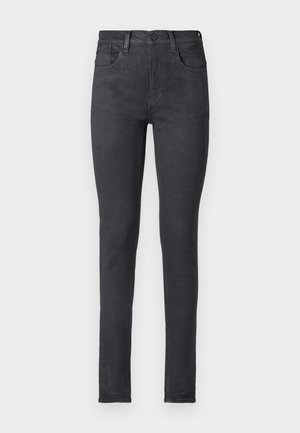 Jean skinny en denim noir avec une taille mi-haute, cinq poches et un zip. Texture lisse et silhouette ajustée.