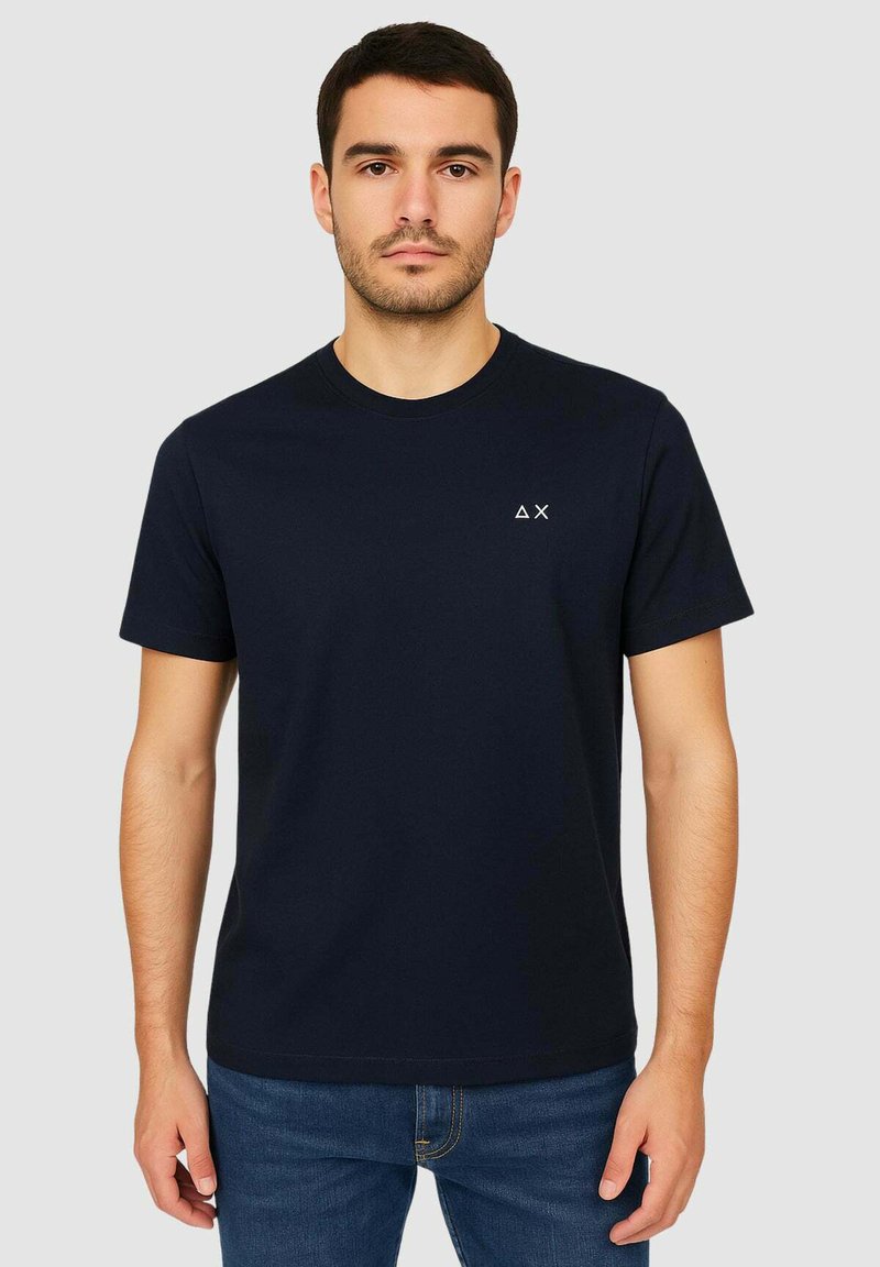 Maglietta in cotone blu navy con collo rotondo e maniche corte, caratterizzata da un piccolo logo bianco sulla parte sinistra del petto. Tessuto liscio.