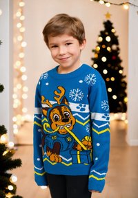 Maglione blu lavorato a maglia con un cane dei cartoni animati con corna, motivi di fiocchi di neve e regali. Polsini e orlo a coste, contrasto di colori vivace.