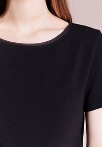 Black short-sleeve t-shirt featuring a round neckline with a subtle textured trim. Made from a soft, lightweight fabric.