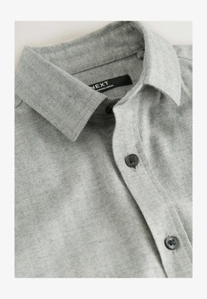 Hall hallatud halli herringbone mustriga särk kraega, mustade nuppudega ja väikese sildiga, millel on kiri "NEXT". Pehme tekstuur ja tavaline lõige.