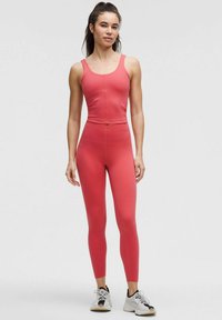Set de îmbrăcăminte activă ajustată în coral, format dintr-un top scurt și leggings cu talie înaltă. Material neted, elastic, cu cusături minime.