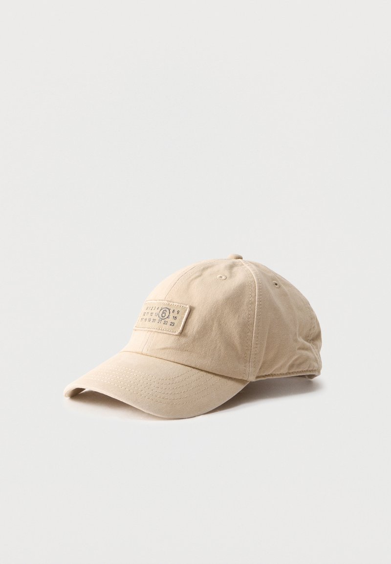 Μπεζ βαμβακερό καπέλο μπέιζμπολ με ραμμένη ετικέτα που εμφανίζει μια σειρά αριθμών στον μπροστινό πίνακα, τοποθετημένο σε απλό ανοιχτό φόντο.