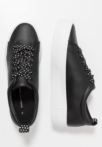 Černé tenisky z umělé kůže s bílou platformou, ozdobnými tkaničkami s puntíky a poutkem na patě.