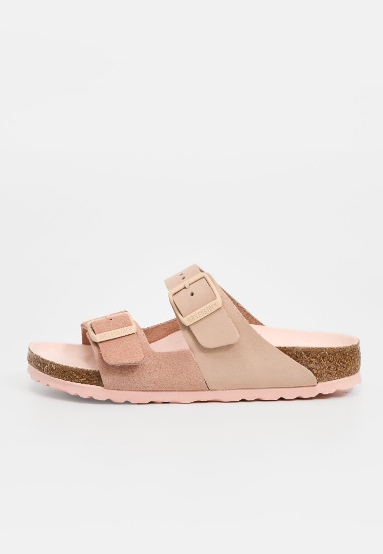 Tanfarbene Wildledersandalen mit zwei verstellbaren Riemen, Korkfußbett und hellrosa Außensohle. Flaches Design mit glatter Textur und dezentem Branding.