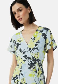 Blumenwickelkleid in Hellblau mit gelben und schwarzen Akzenten. Verfügt über kurze, flatternde Ärmel und ein tailliertes Detail. Glatte Textur.