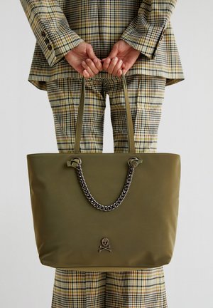 Borsa tote verde oliva con finitura liscia, accento in catena argentata e un emblema di teschio sul davanti. Dotata di manici lunghi.