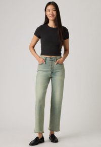 Τζιν ψηλόμεσο με ευθεία γραμμή σε ανοιχτό μπλε-πράσινο χρώμα, κατασκευασμένο από denim, με κούμπωμα με κουμπιά, δύο μπροστινές τσέπες και διακοσμητικές ραφές.