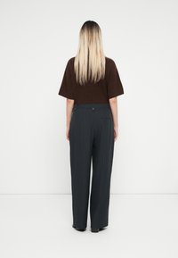 Brun strikket topp med korte ermer, kombinert med mørkegrå stripete vide bukser, med knapplukking og baklomme.