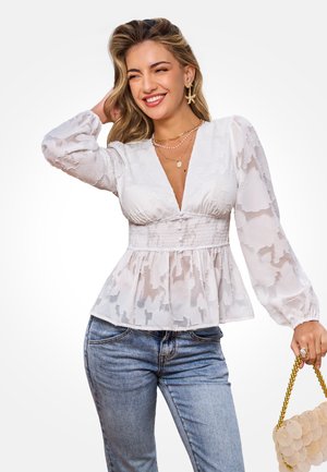 Witte blouse met textuur, pofmouwen, een geplooide taille en diepe V-hals; gecombineerd met lichtblauwe spijkerbroek en een beige ronde tas.