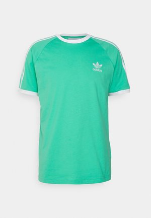 Camiseta de manga corta verde de Adidas con cuello blanco, puños en las mangas, tres rayas en el hombro y el logo de trébol de Adidas en el pecho izquierdo.