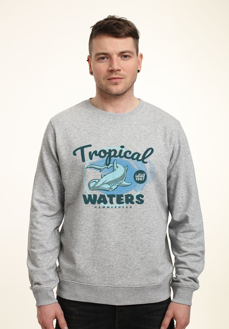 Felpa grigia con un design grafico di uno squalo martello, accompagnata dal testo "Acque Tropicali" e "isola 1967".
