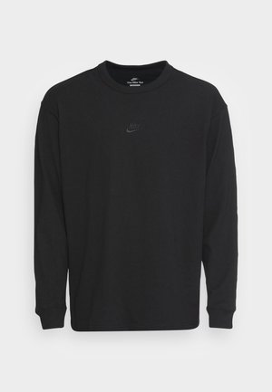 Black long-sleeve shirt made of cotton, featuring a ribbed crew neckline, relaxed fit, and a small black Nike logo at the chest.