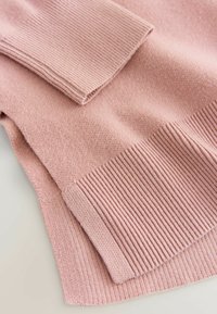 Hele hõbe roosa kudumiga kampsun, millel on sooniktekstuur varrukatel ja ääreline, pehme ning sile välimus.