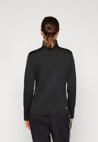 Pullover nero a maniche lunghe con colletto alto, realizzato in tessuto morbido, caratterizzato da una forma attillata e un design minimalista.
