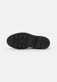 Semelle de chaussure en caoutchouc noir avec des profondeurs de crantage et des accents texturés, présentant une forme arrondie et un talon renforcé pour plus de durabilité.