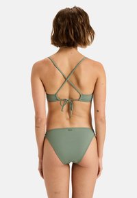 Green bikini set with a crisscross strap design at the back, adjustable tie closure, and a smooth texture. The fabric is matte and stretchy.