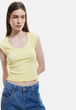 Geel geribd tanktop met een ronde hals, fitted design en korte mouwen, gecombineerd met blauwe high-waisted denim jeans.