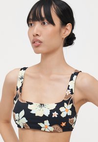 Čierny bikiny top s kvetinovým vzorom a štvorcovým výstrihom, širokými ramienkami. Obsahuje svetlé kvety a hnedé listy pre kontrast.