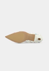 Escarpin à bout pointu à motif floral avec une tige synthétique blanche, une semelle beige et une petite découpe au talon pour faciliter l'enfilage.