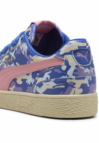 Zapatillas PUMA con un patrón de camuflaje en azul, púrpura y crema, que presentan una franja de ante rosa, una suela de goma texturizada y un collar acolchado.